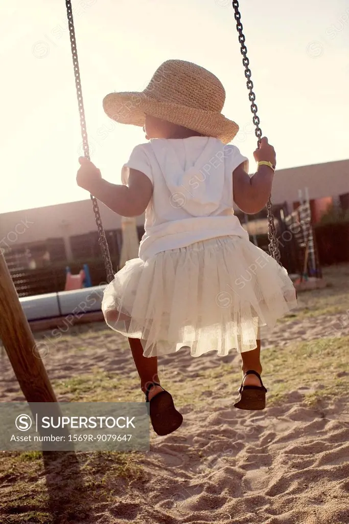 Little girl sitting on swing, rear view