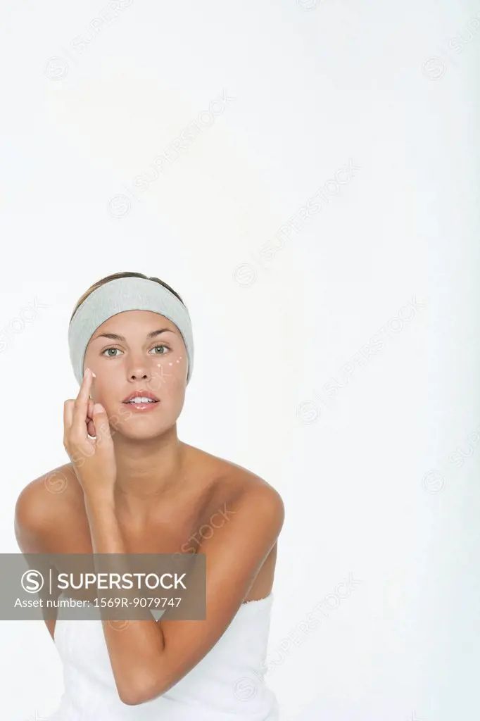Young woman moisturizing her face