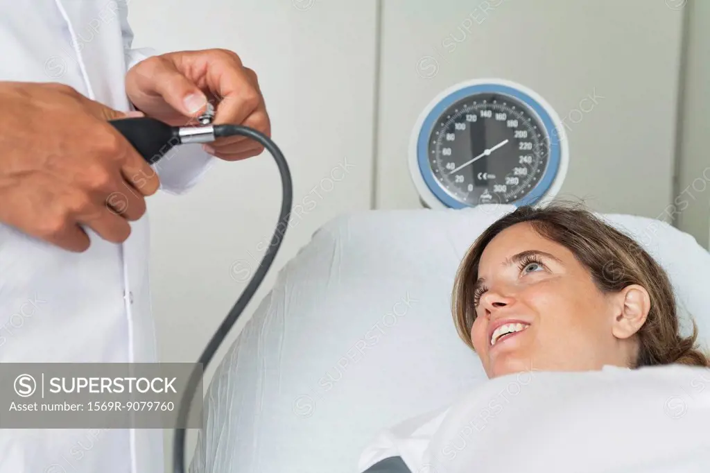 Young woman lying on examination table while doctor checks her blood pressure