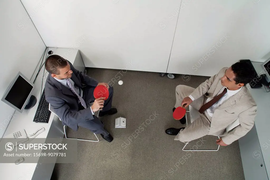 Colleagues hitting ping pong ball back and forth in office cubicle