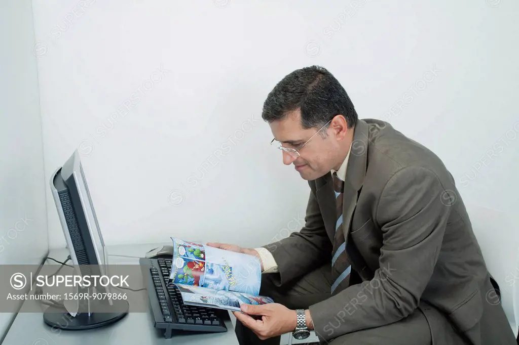 Mature man reading comic book in office cubicle