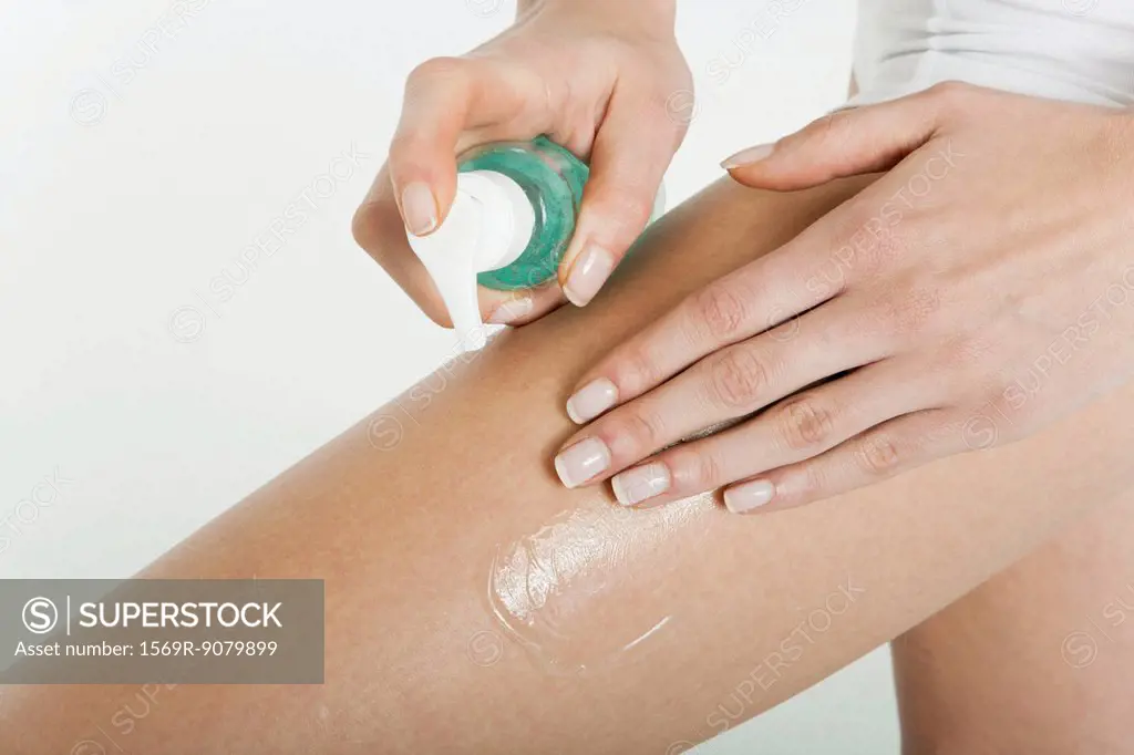 Woman moisturizing bare leg, cropped