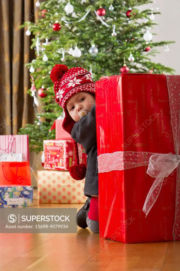 Baby girl peeking at large Christmas present