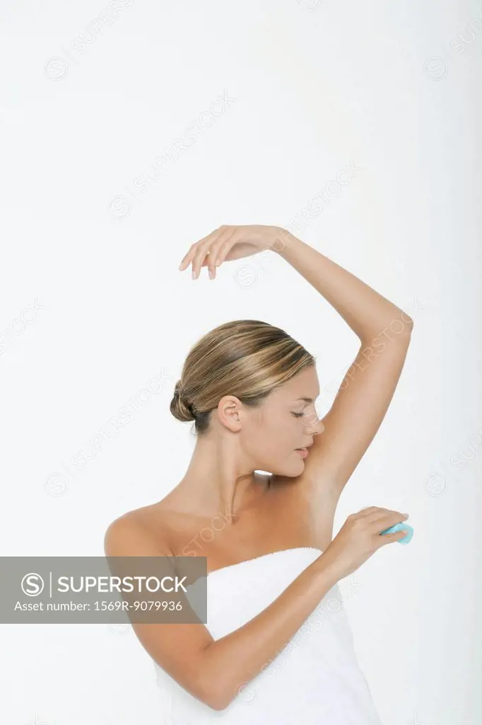 Young woman applying underarm deodorant