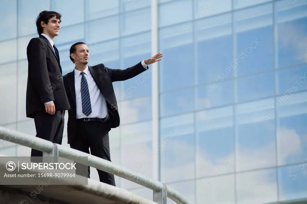 Business associates standing together outdoors, one pointing
