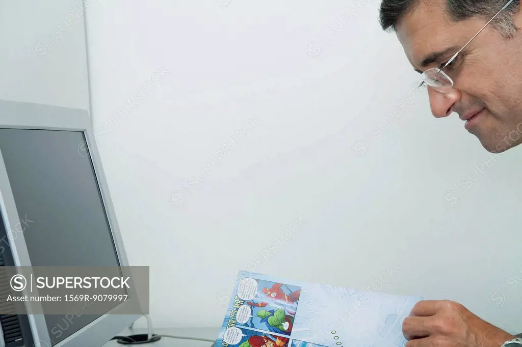 Mature man reading comic book in office