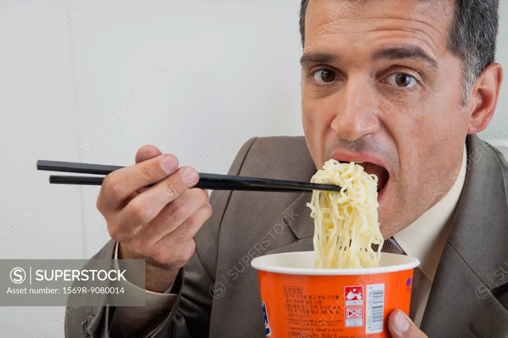 Mature businessman eating ramen noodles