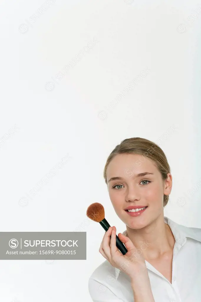 Preteen girl holding make_up brush, portrait