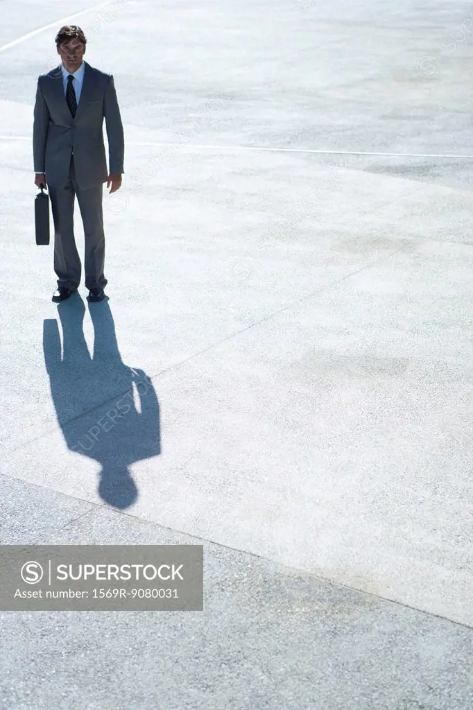 Businessman standing outdoors with briefcase in hand