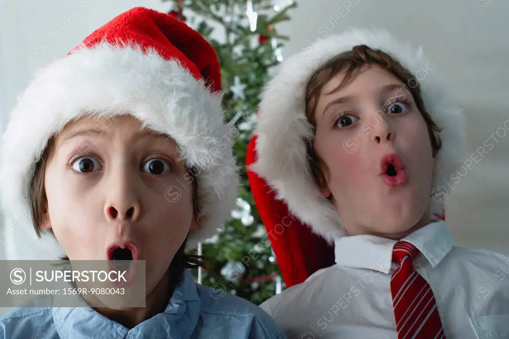 Boys wearing Santa hats, making surprised faces