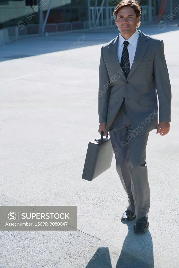 Businessman walking outdoors with briefcase in hand