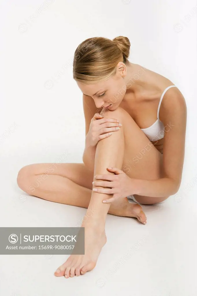 Young woman sitting in underwear, resting chin on knee