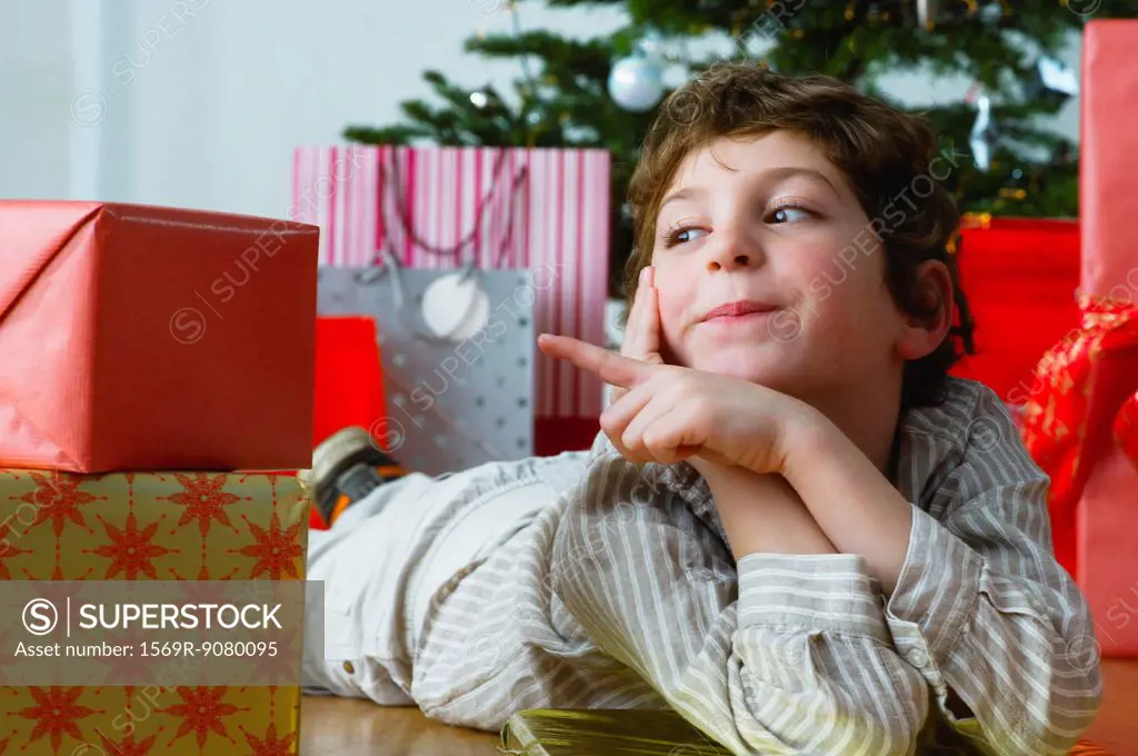 Boy lying on floor pointing at Christmas presents