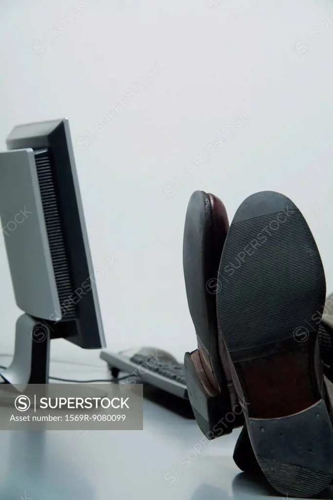 Businessman with feet up on desk in office, cropped
