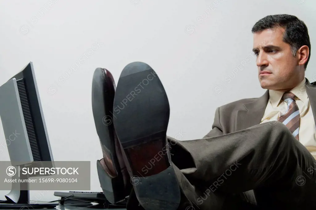 Businessman sitting in office with feet up on desk
