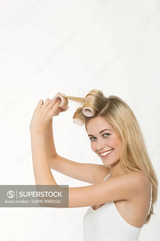 Teen girl rolling her hair with curlers