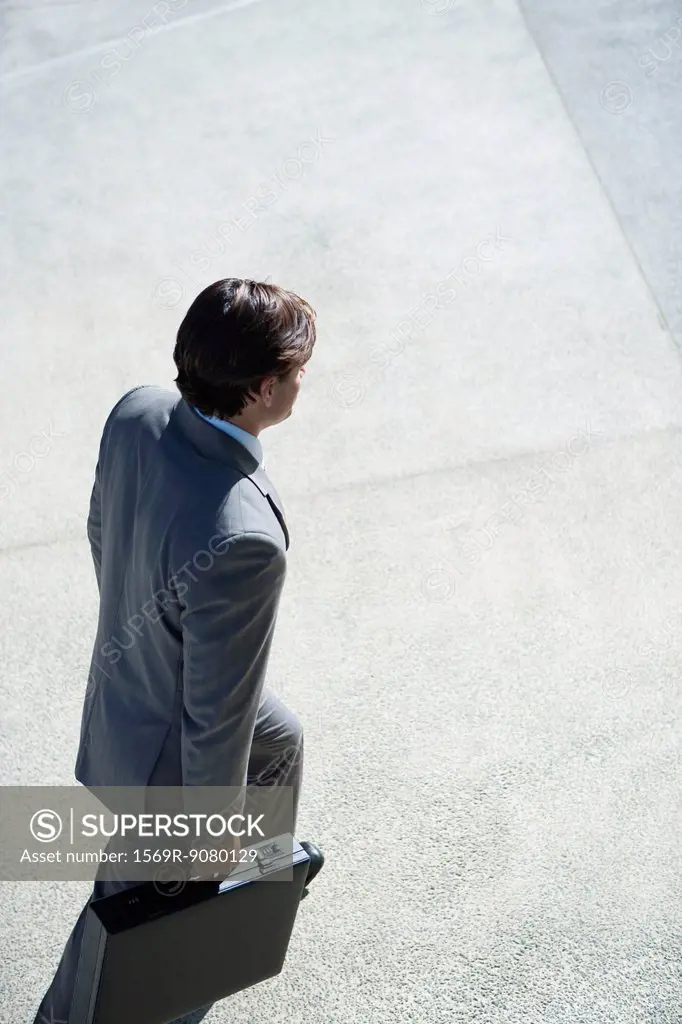 Businessman walking with briefcase in hands, elevated view