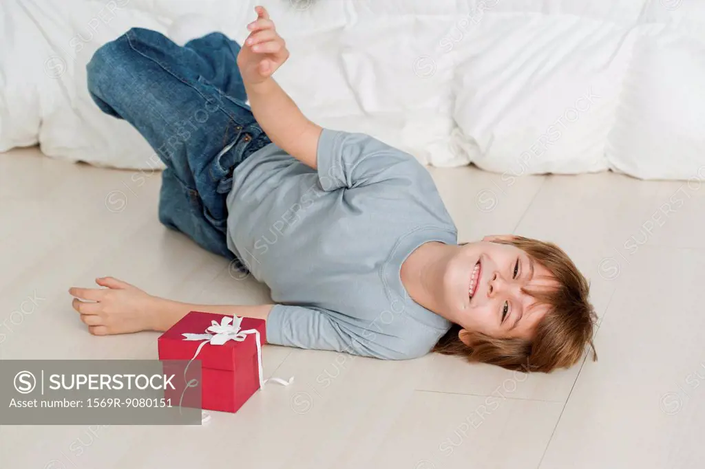 Boy lying on floor beside gift box