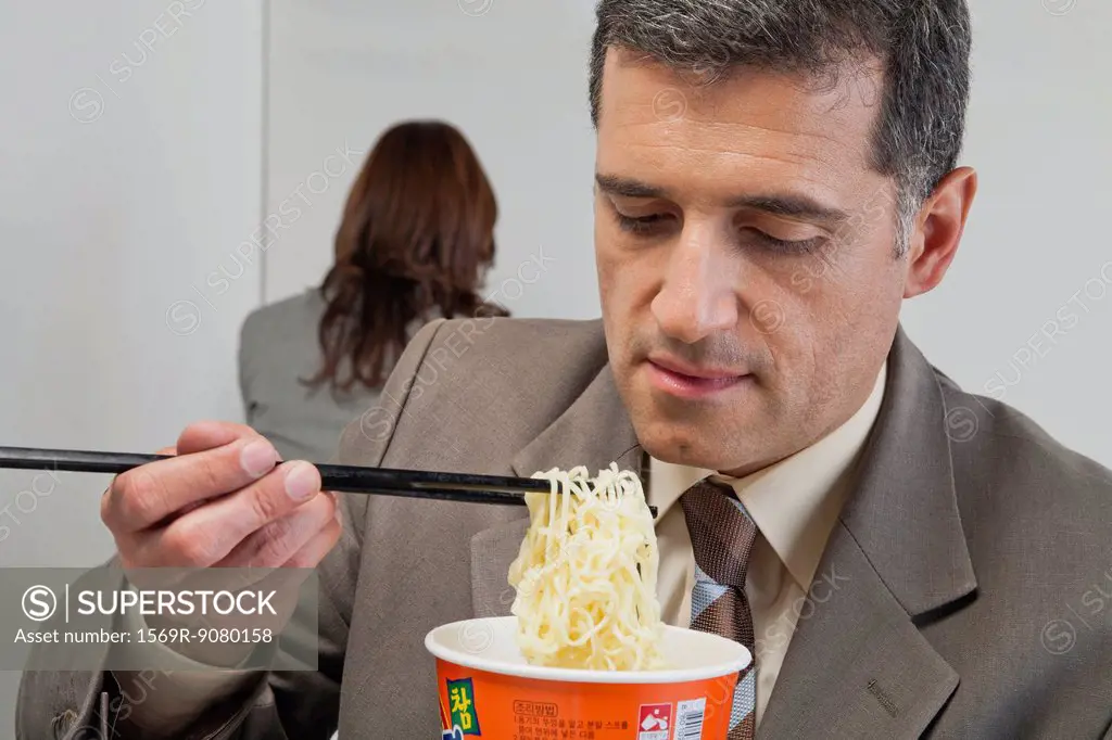 Businessman eating ramen noodles in office