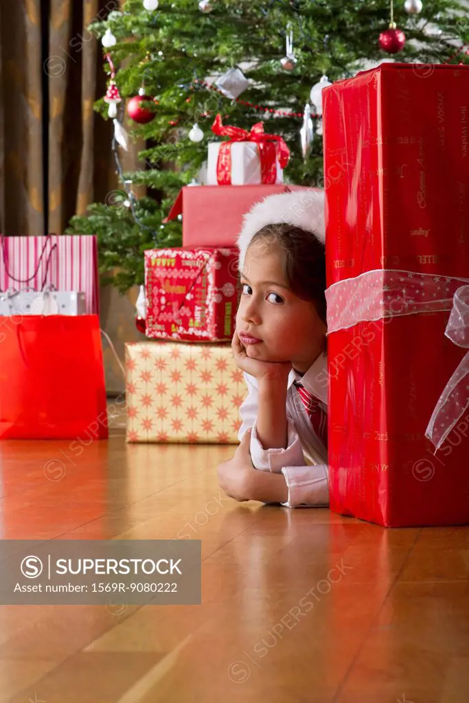 Boy waiting impatiently behind large Christmas present