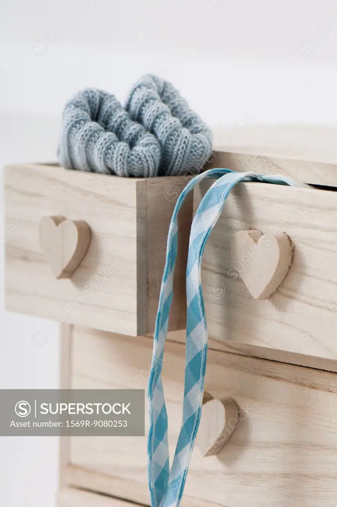 Clothing hanging out of wooden drawers with heart shaped knobs