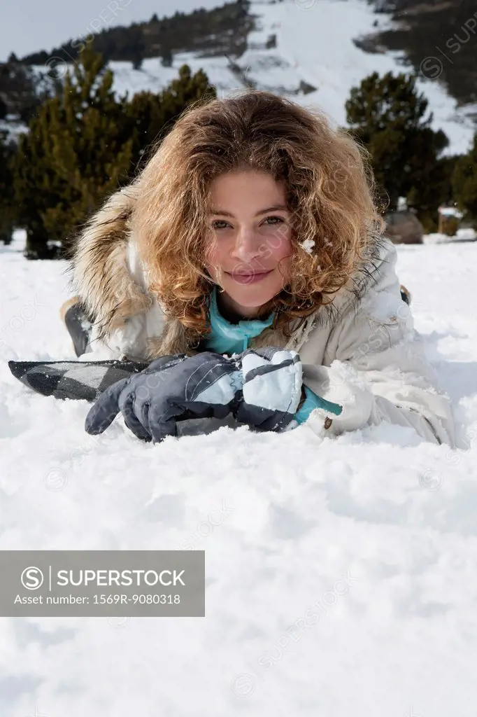 Preteen girl lying in snow, portrait