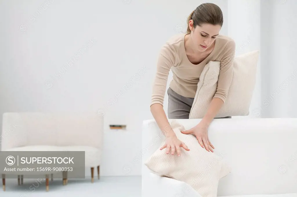 Woman arranging pillows on sofa
