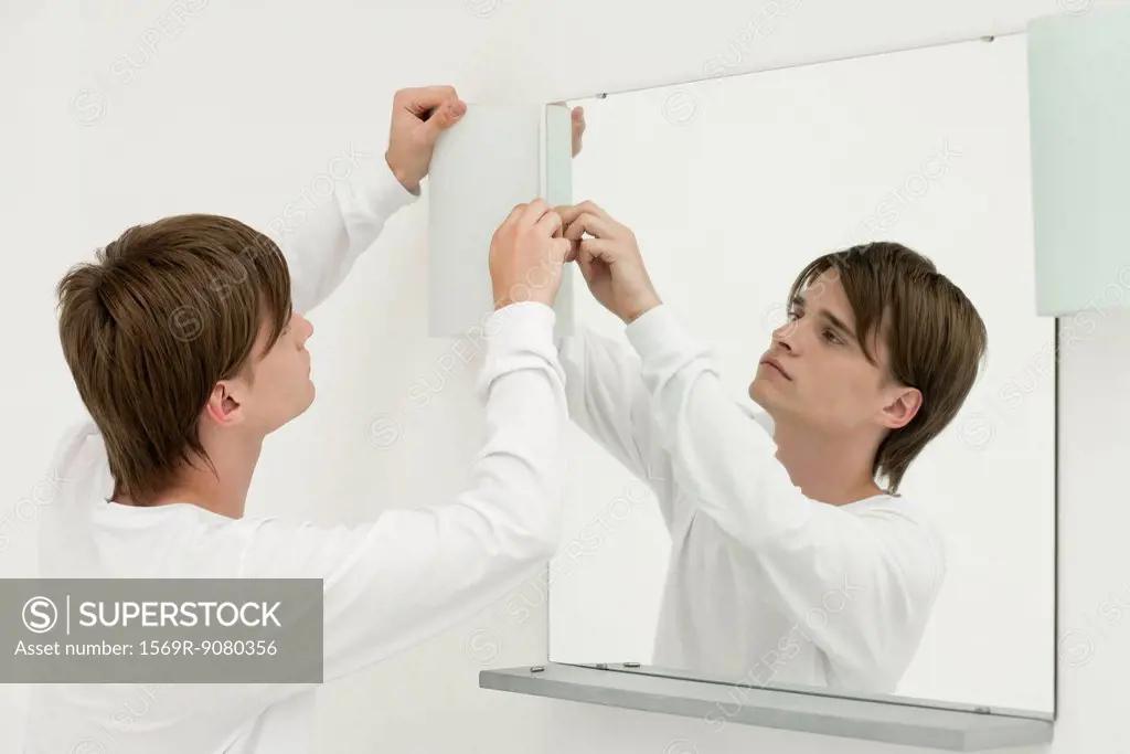 Young man repairing wall light in bathroom