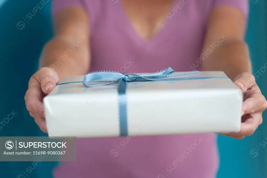 Woman holding out present, mid section