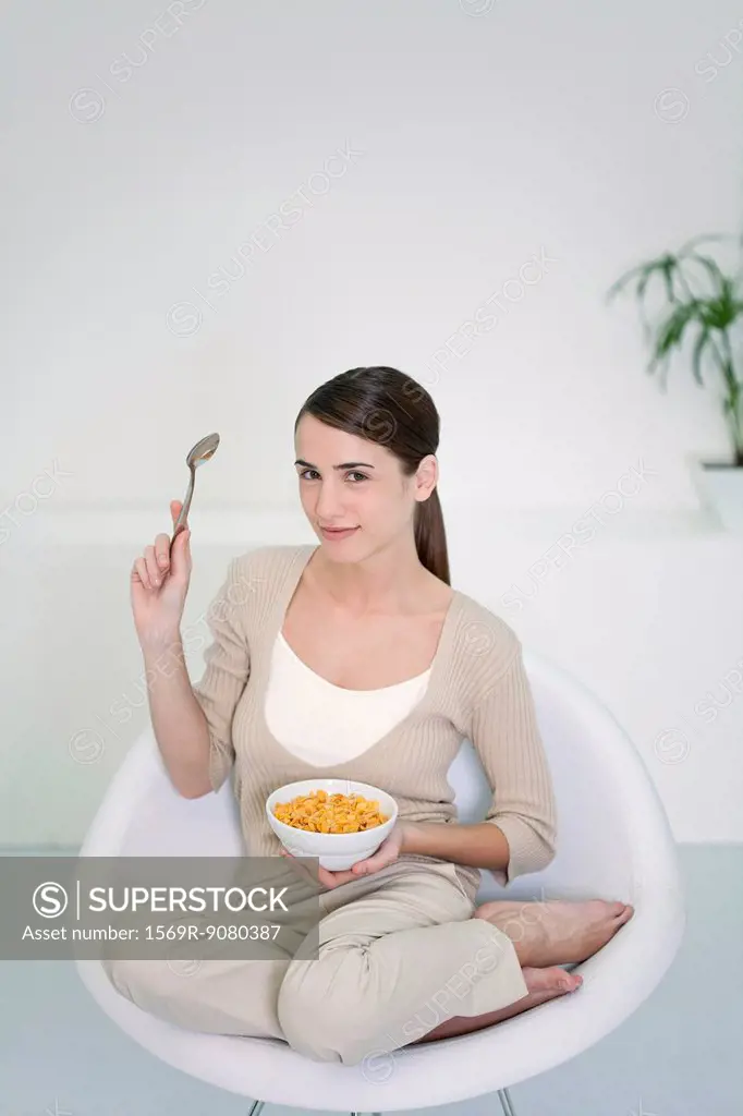 Young woman sitting in chair with bowl of cereal
