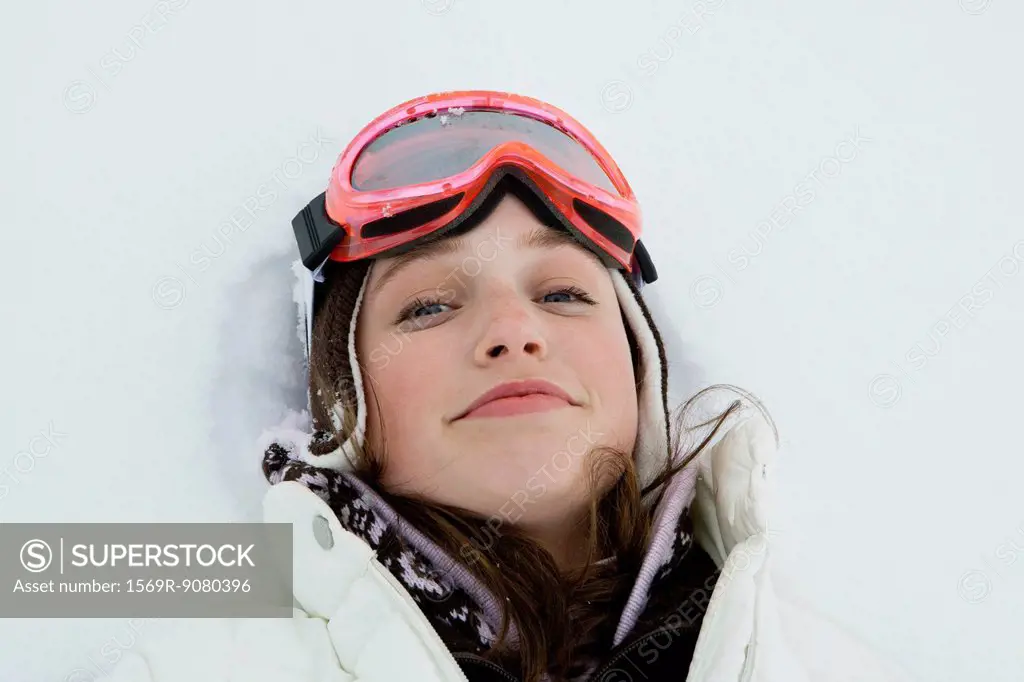 Teenage girl in ski outfit lying in snow