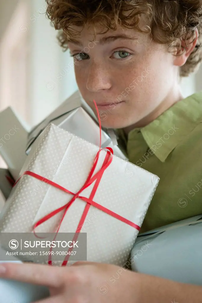 Preteen boy holding pile of presents
