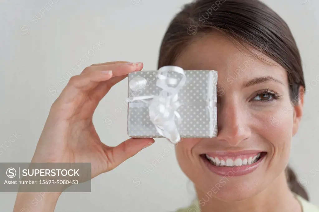 Young woman covering eye with gift