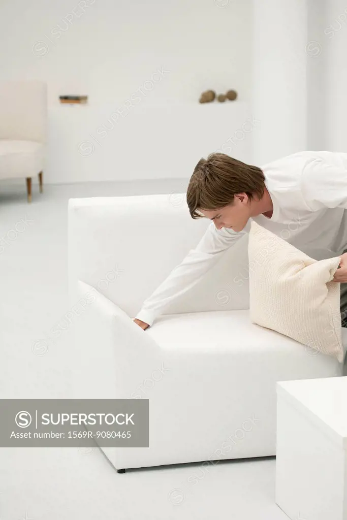 Young man tidying sofa