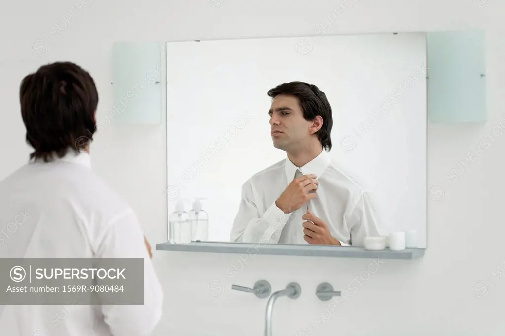 Man adjusting shirt collar in mirror