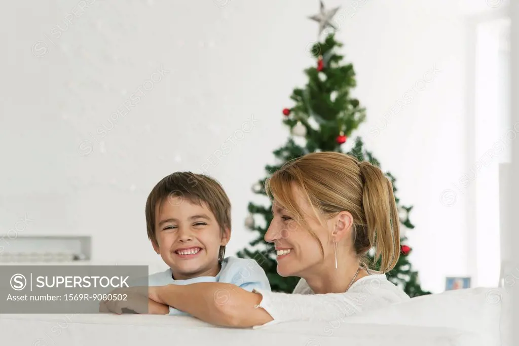 Mother and son sitting in couch in front of Christmas tree