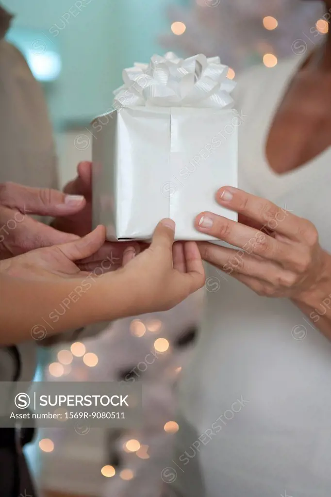 Man, woman and child´s hands holding gift together, cropped
