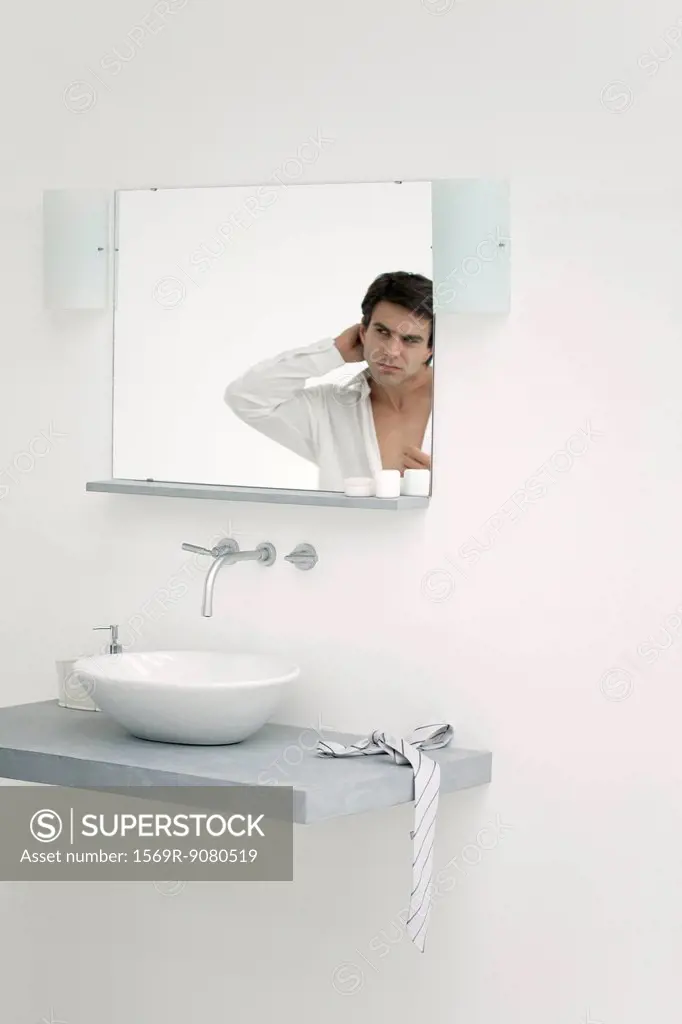 Man looking at self in bathroom mirror