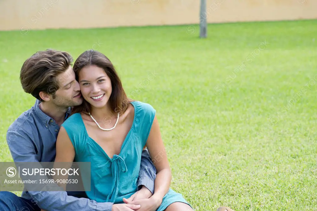Young man kissing girlfriend on cheek