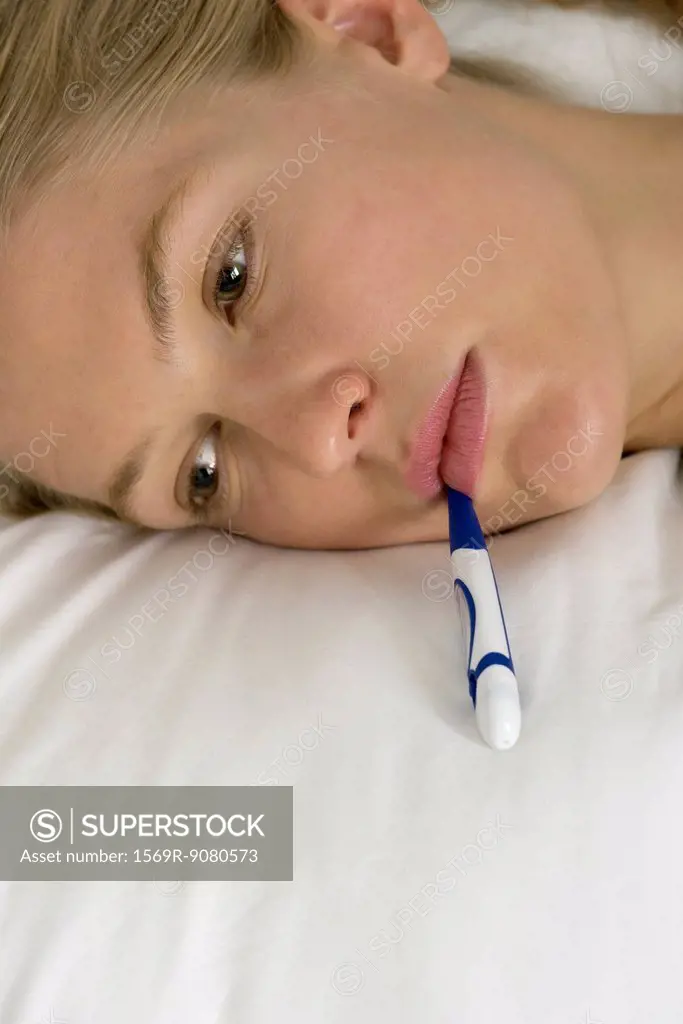 Young woman with thermometer in mouth, cropped