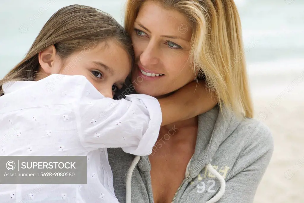 Mother and young daughter embracing outdoors