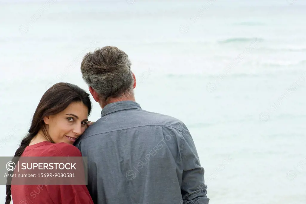 Couple together at water´s edge, woman smiling over shoulder