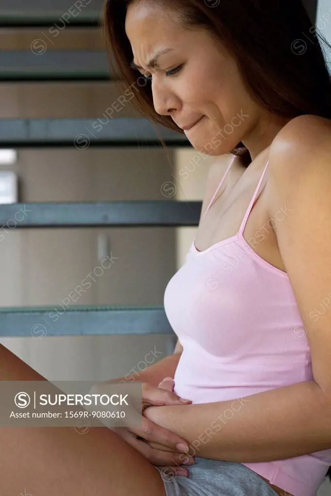 Young woman clutching abdomen in pain
