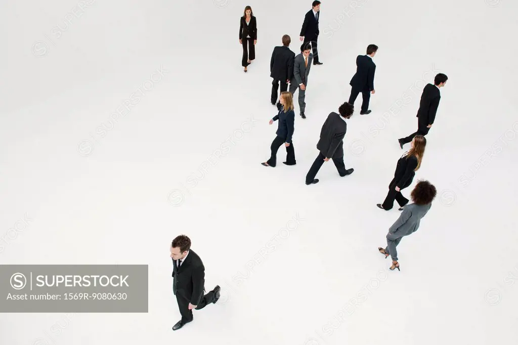 Businessman walking alone in opposite direction of other business professionals