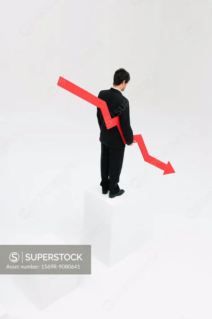 Businessman standing at top of steps holding arrow pointed downward
