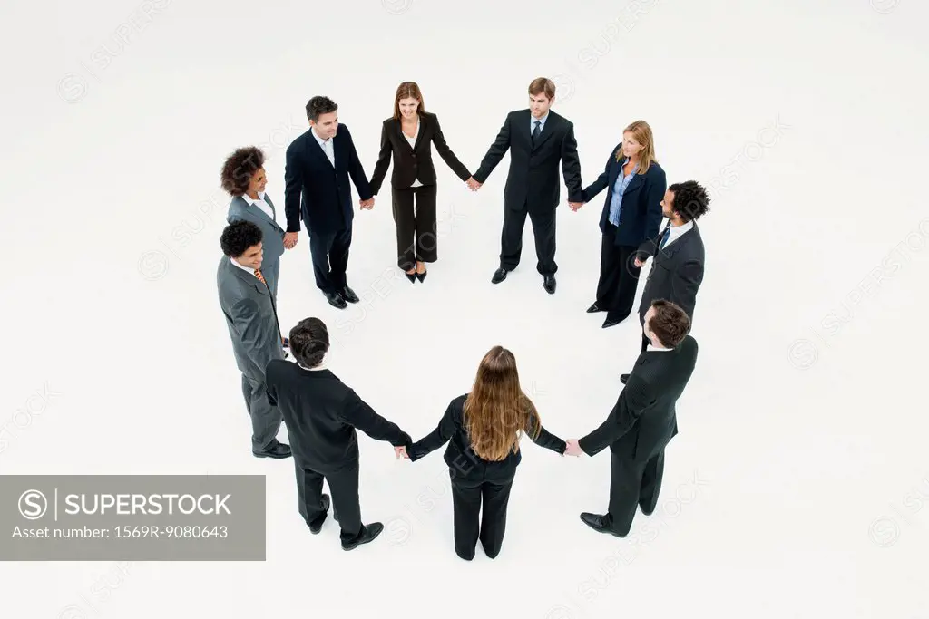 Businessmen and businesswomen standing together in circle holding hands