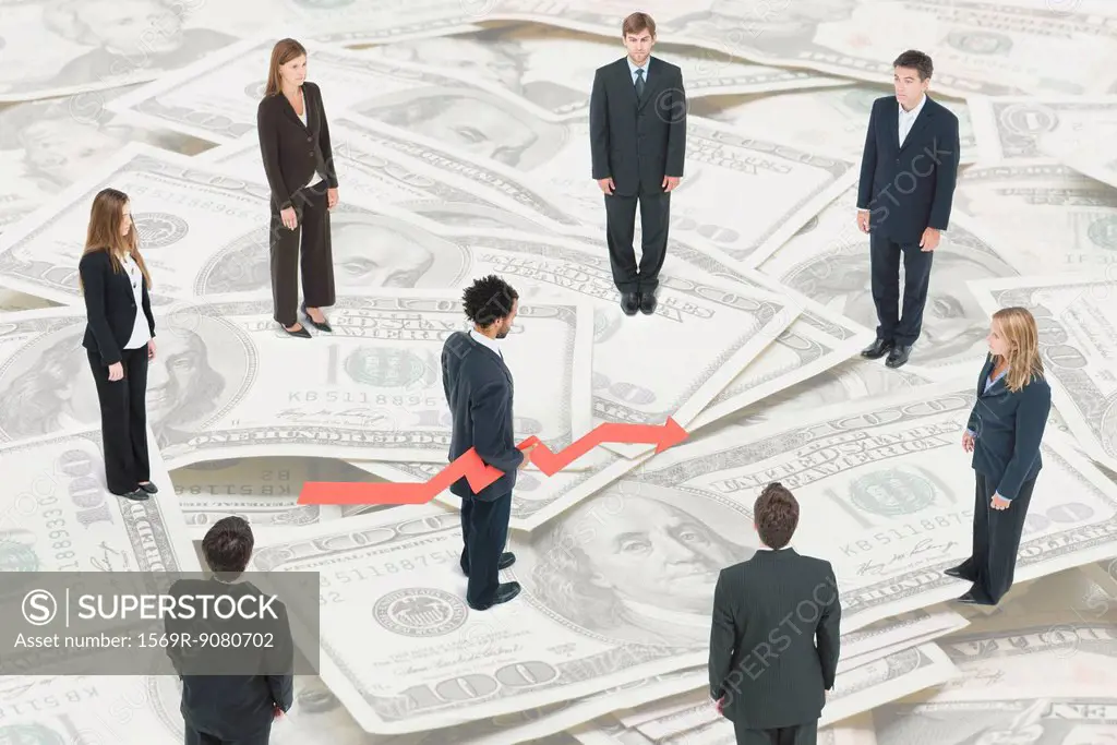 Executives standing on large pile of money around man holding arrow forecasting financial future