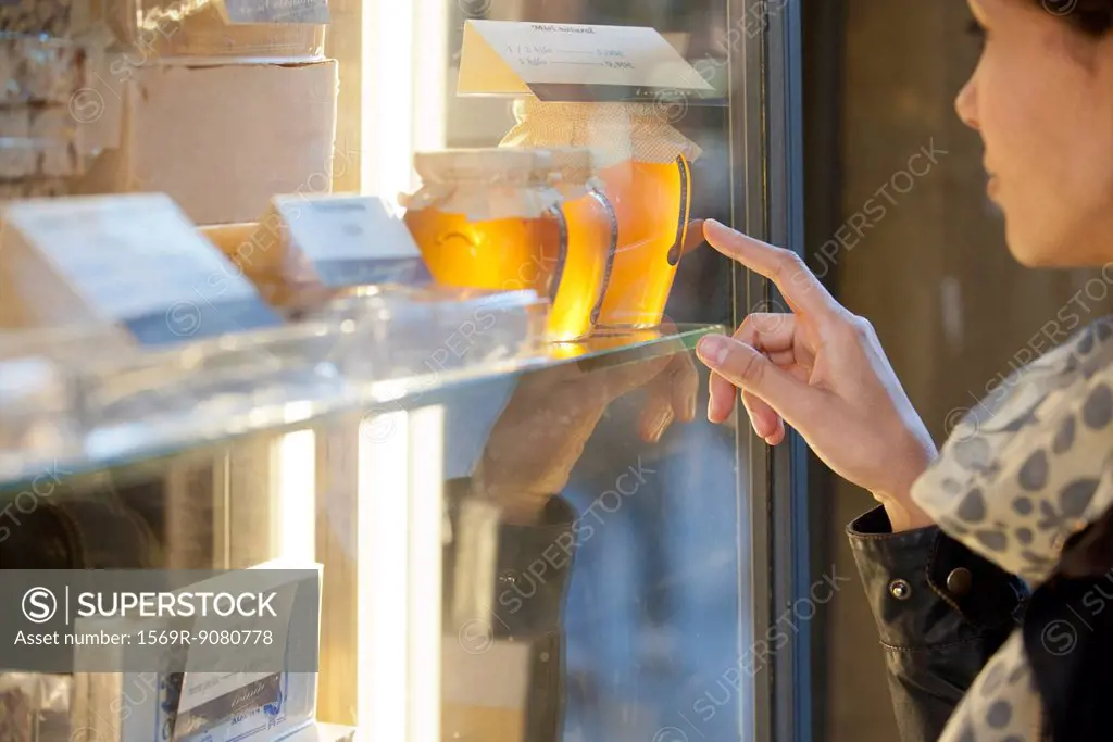 Woman looking at jars of honey in shop window