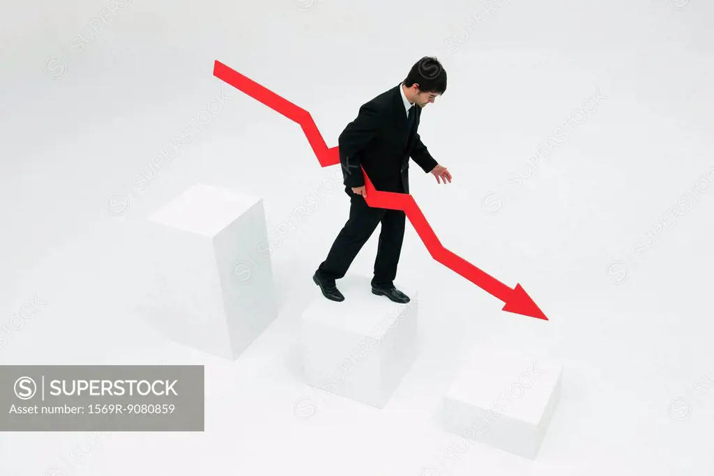 Businessman descending steps holding arrow pointed downward