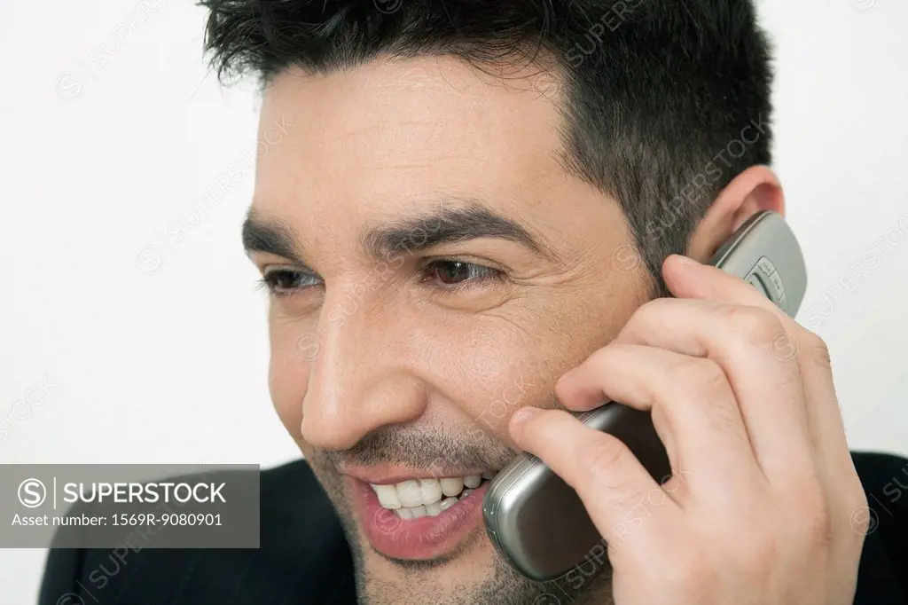 Mid-adult businessman talking on cell phone, smiling